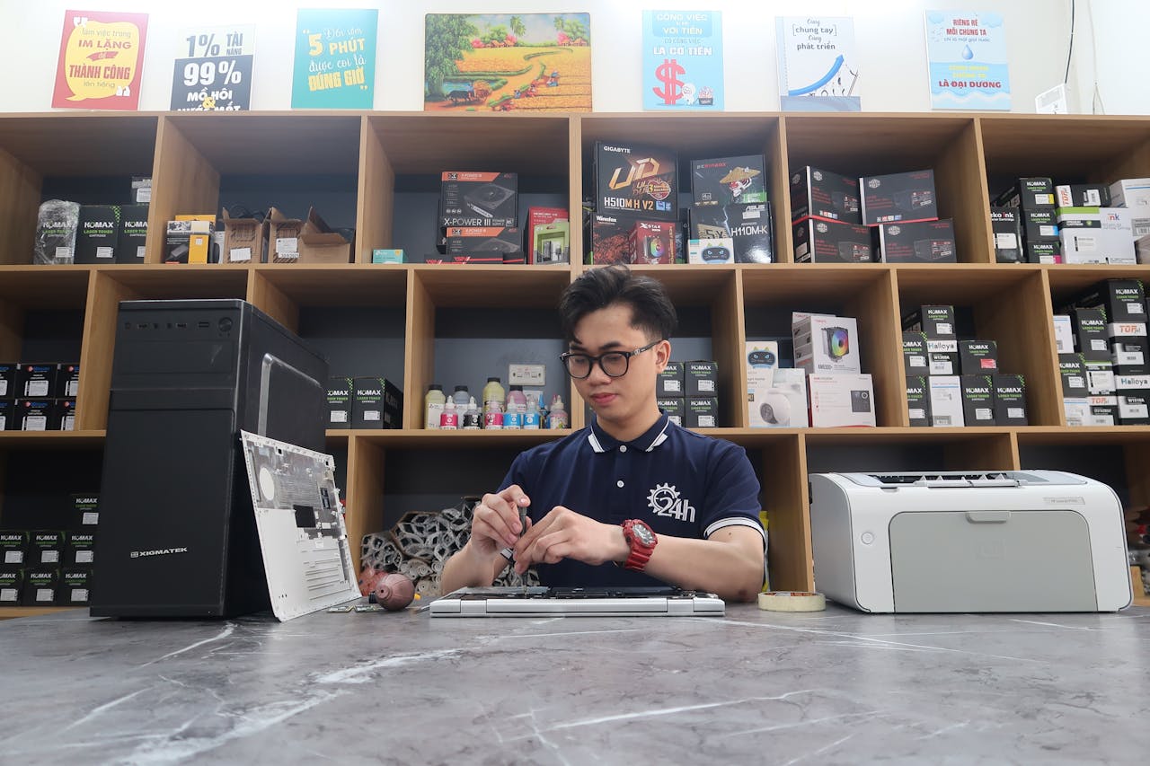 Young technician fixing a computer in a modern electronics store setting.